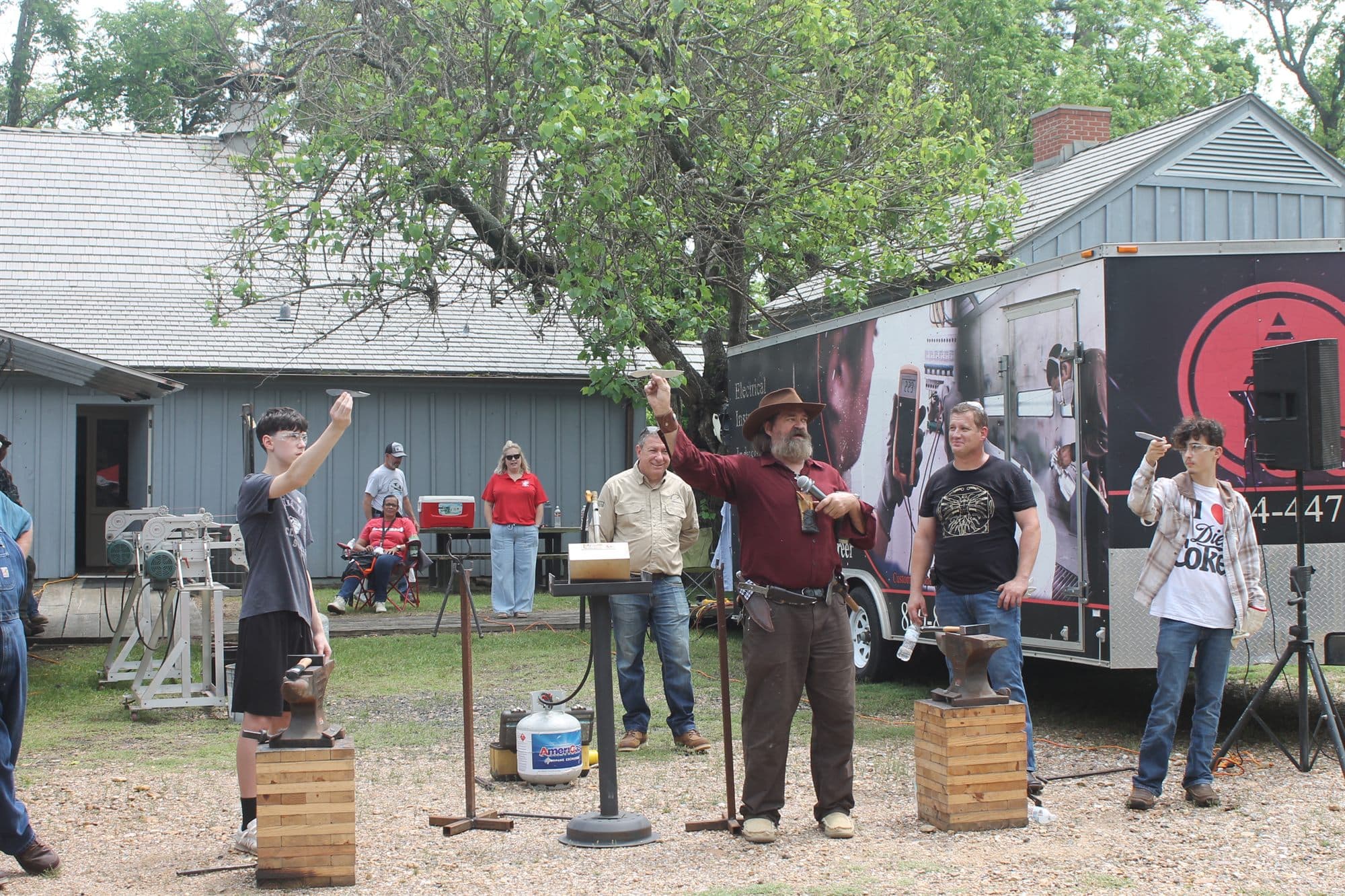 People taking part in an outdoor bladesmithing demonstration at Bowie Festival